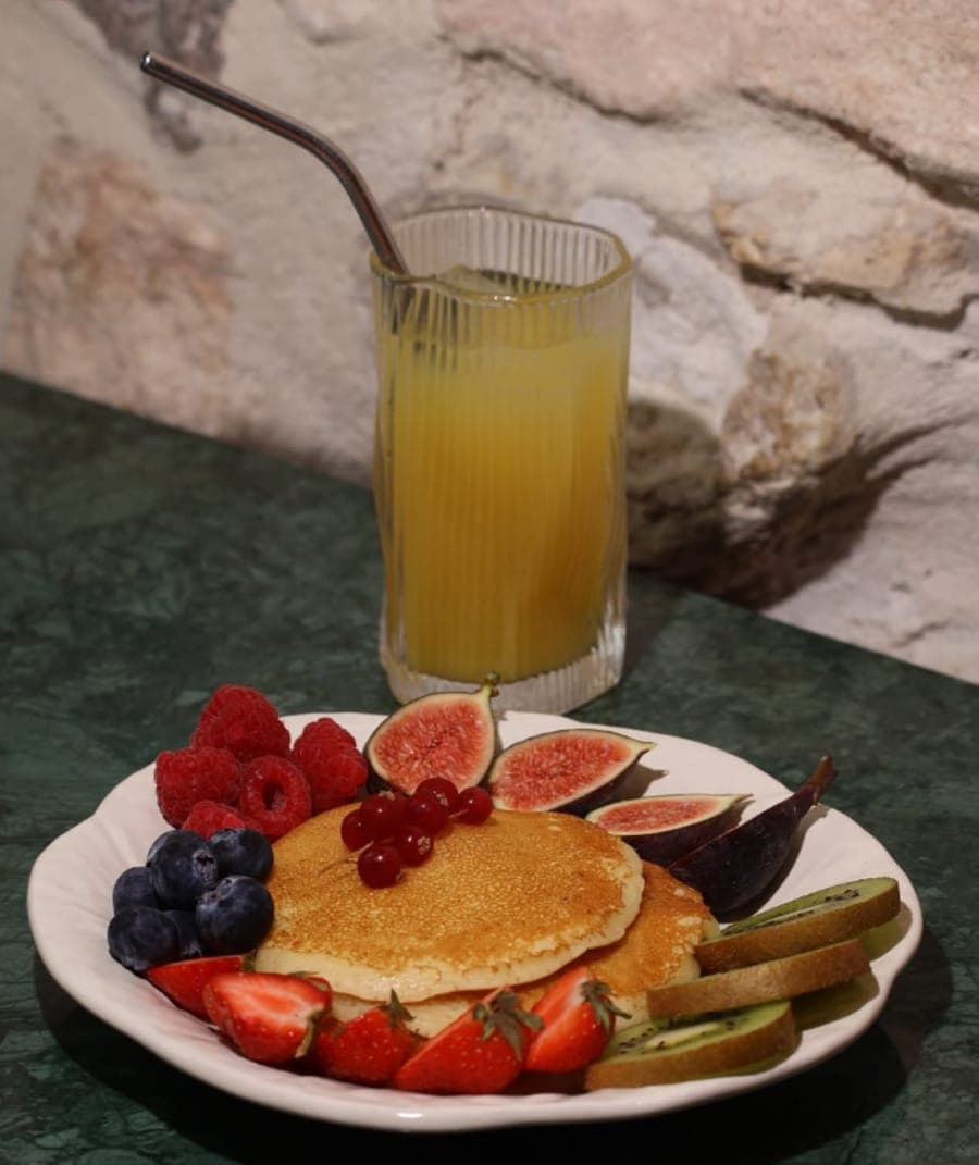 Pancakes aux fruits frais servis avec un jus d'orange pressé sur une table en bois, boissons de la formule brunch
